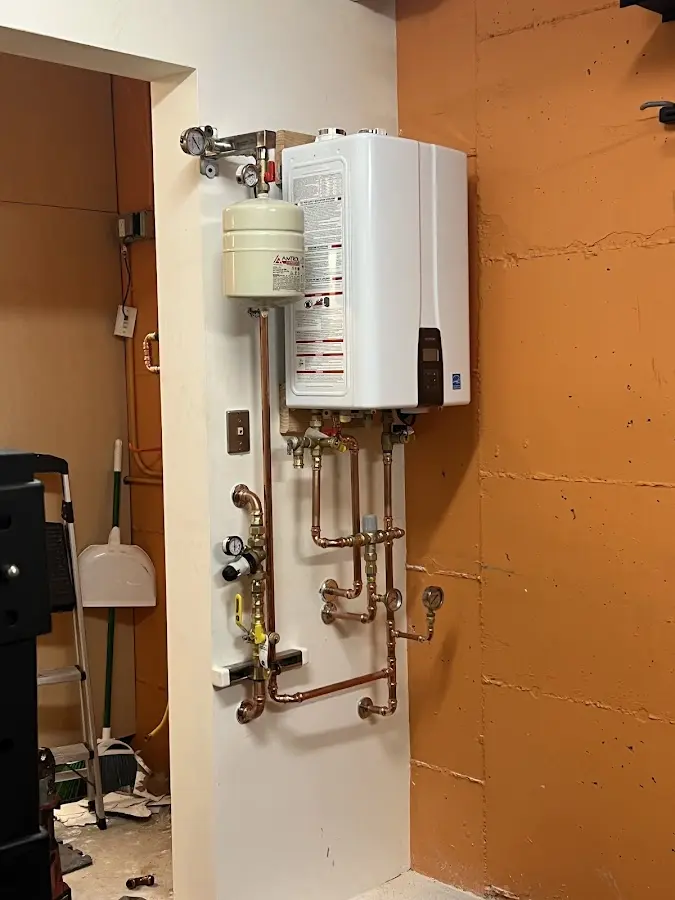 Plumbing technician inspecting water heater connections in Penn Hills